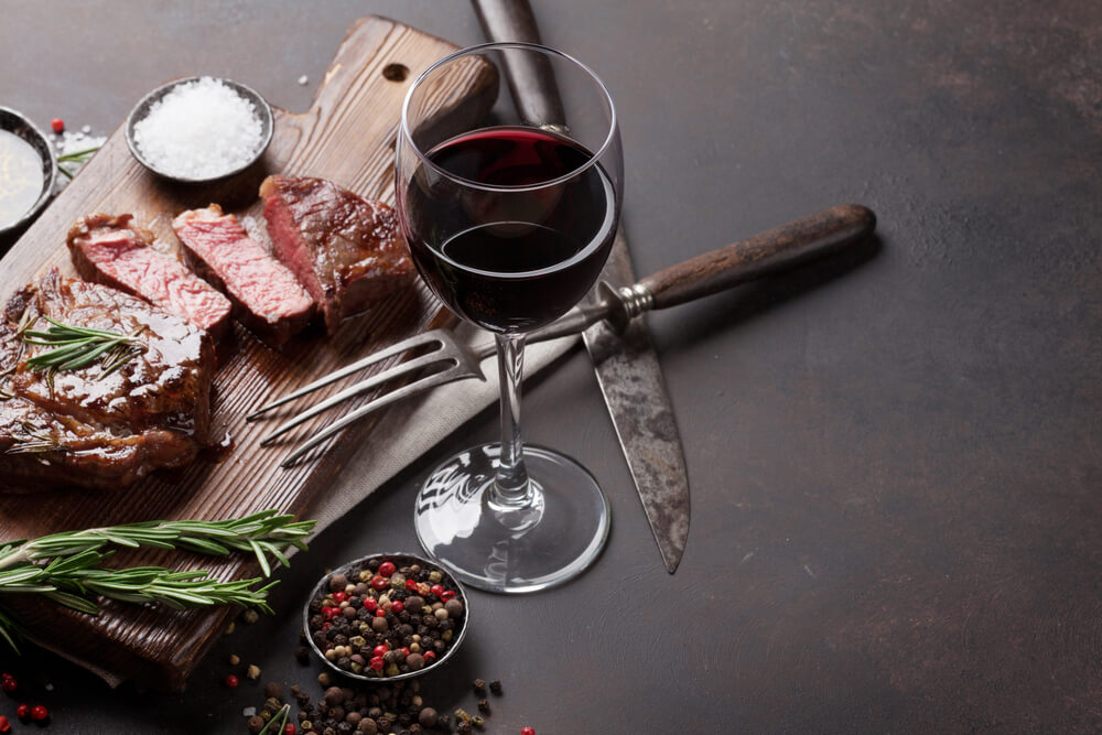 Bistecca di manzo ribeye alla griglia con vino rosso, erbe e spezie sul tavolo di pietra